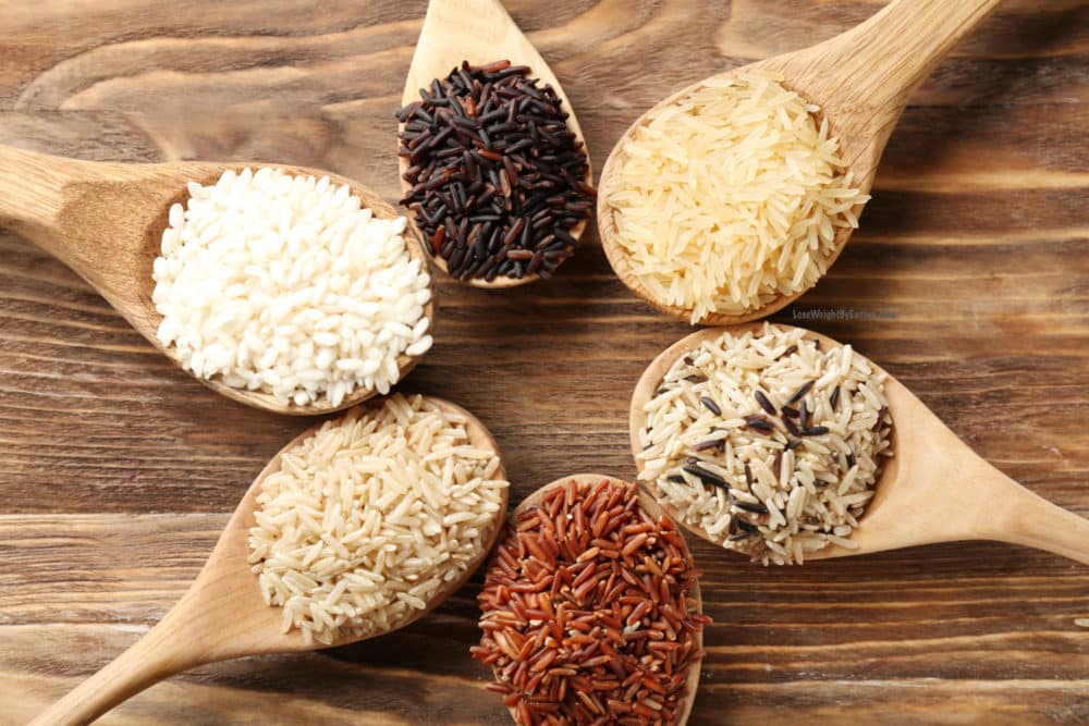 Different types of rice in spoons on wooden background by Roop mahal Rice